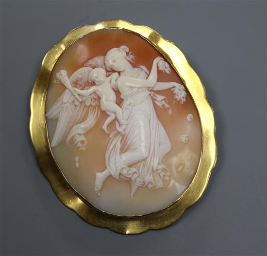 A yellow metal mounted oval cameo brooch, carved with fairy and cherub with cornucopia, 71mm.